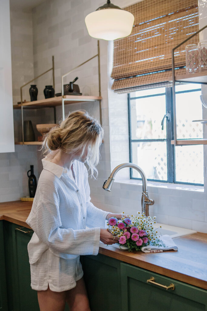 Woman standing at her kitchen sink, preparing a bouquet of fresh flowers.