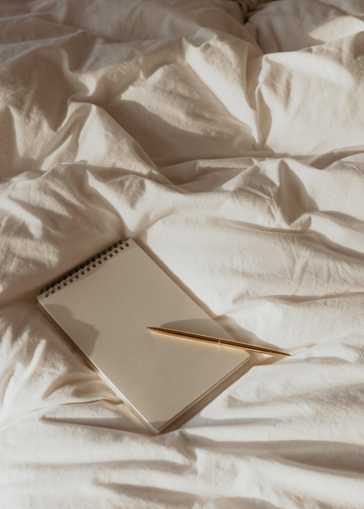 Journal and pen on a bed.