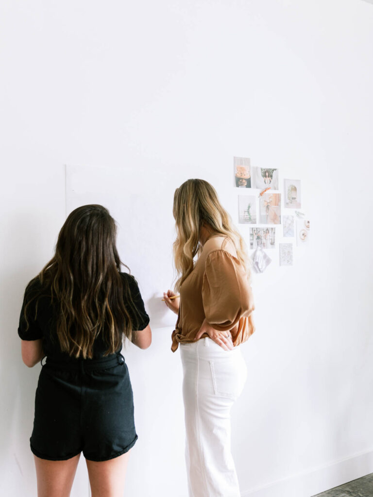 Two women brainstorming on a white board.