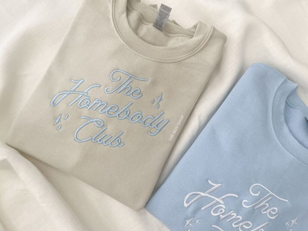 Crewneck sweatshirt embroidered with The Homebody Club in script font.