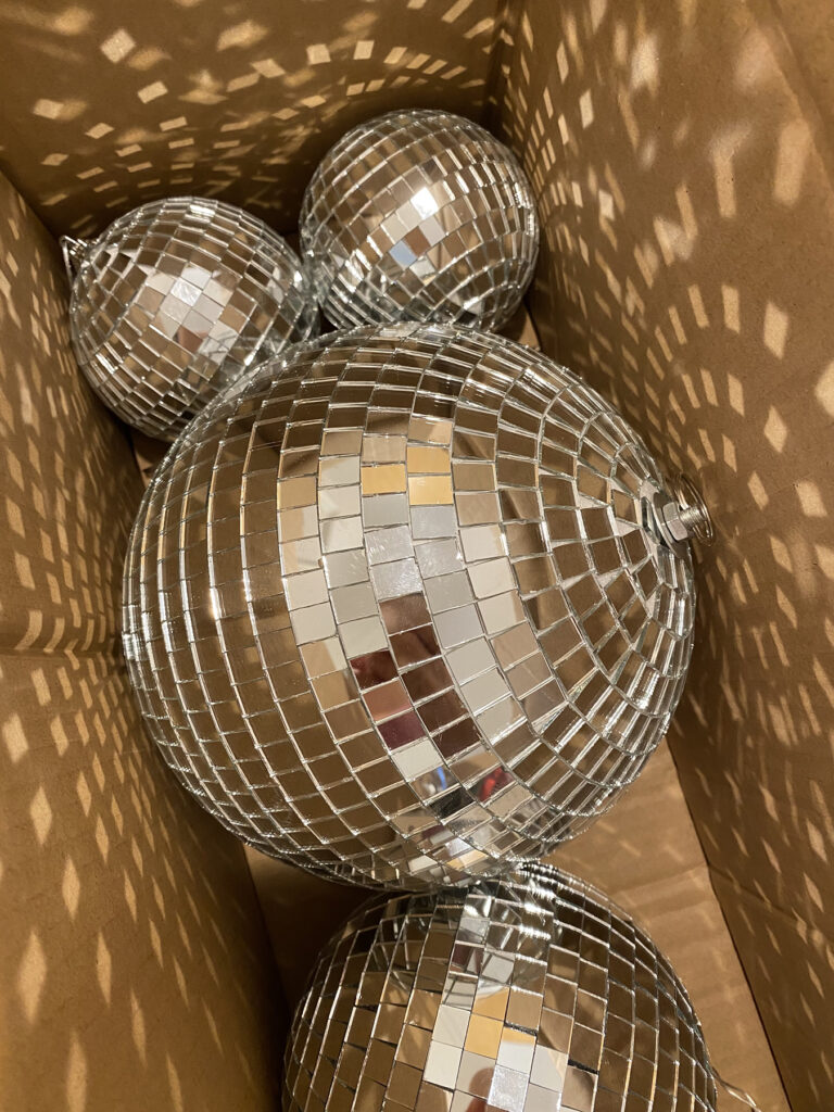 Photo of disco balls in a cardboard box refracting light on the inside of the box.