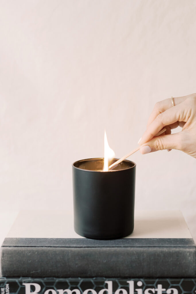 Hand lighting a candle with a match. Represents hygge for introverts concept of creating the right ambience.